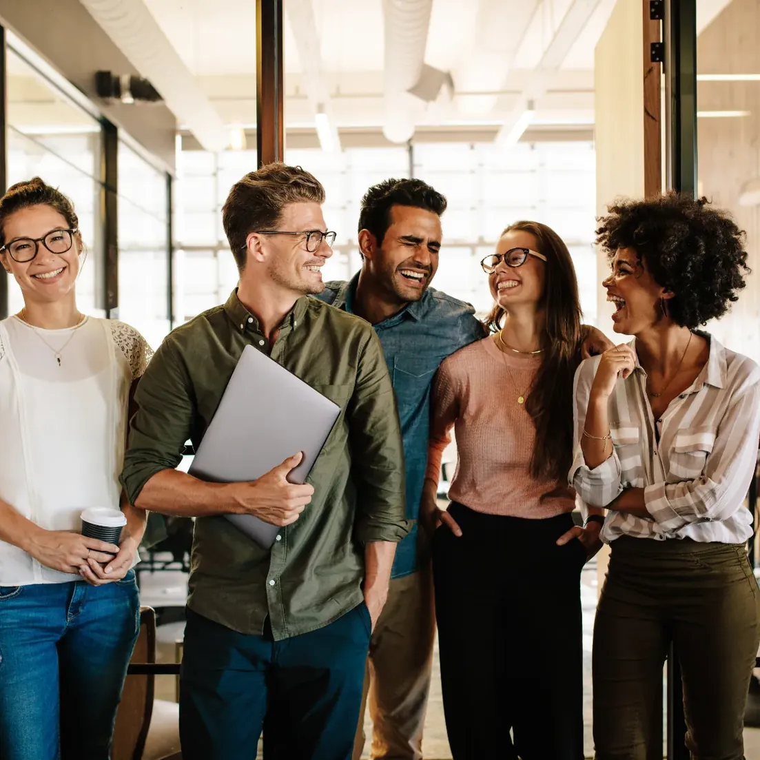 Colegas de trabalho conversando em pé num escritório iluminado